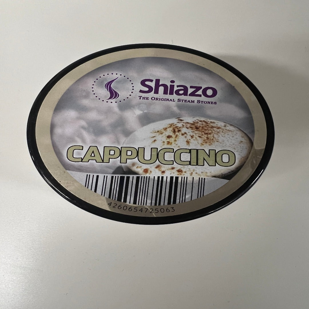 Kuva Shiazo Höyrykivet Cappuccino 100g pakkauksesta, jossa näkyy kermaisen kahvin höyryä ja shisha-pieniä kiviä.