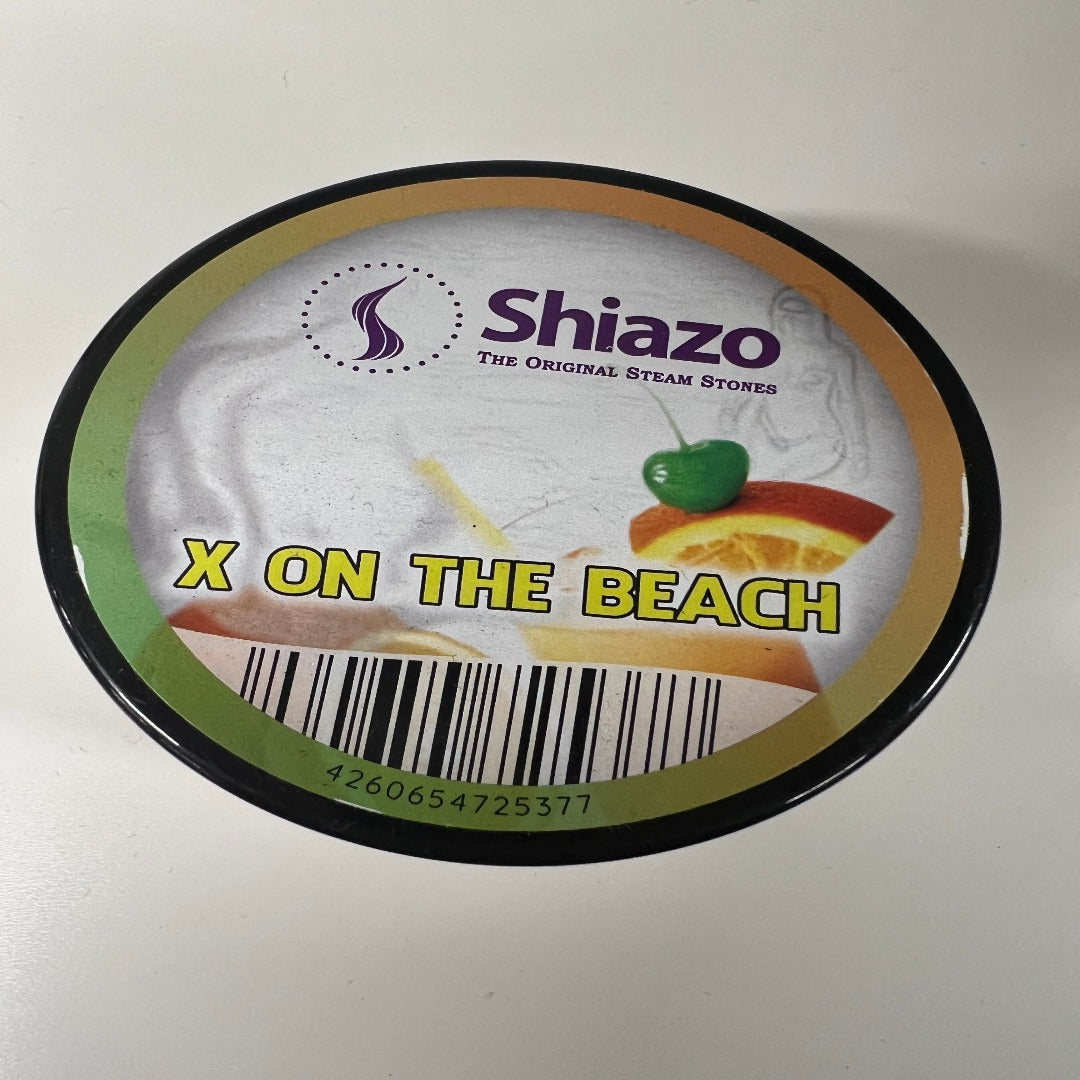 Shiazo Höyrykivet X-On-The-Beach 100g purkki avattuna, sisältäen valkoisia, aromaattisia mineraalikiviä trooppisen hedelmän taustalla.